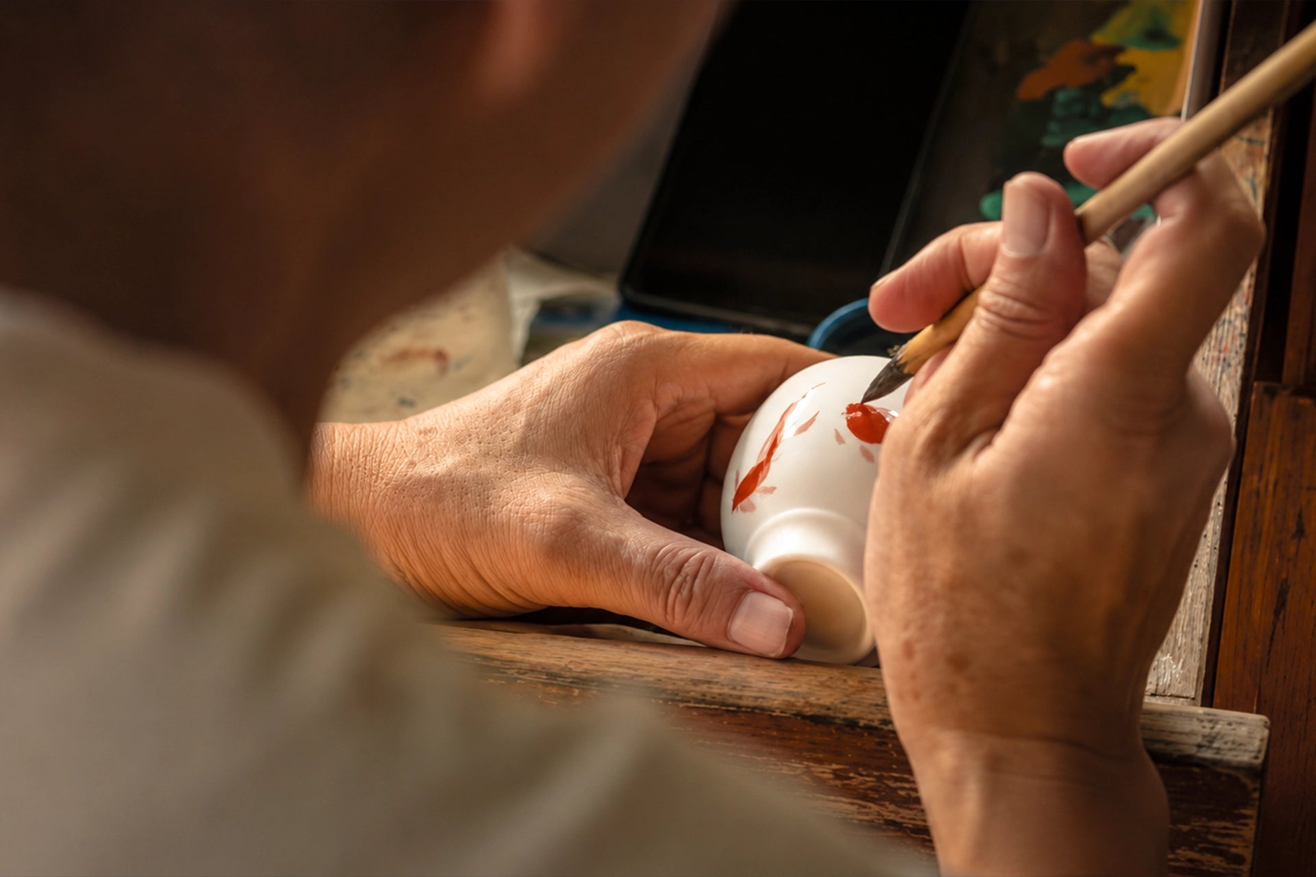 A maker hand-painting a ceramic pet memorial