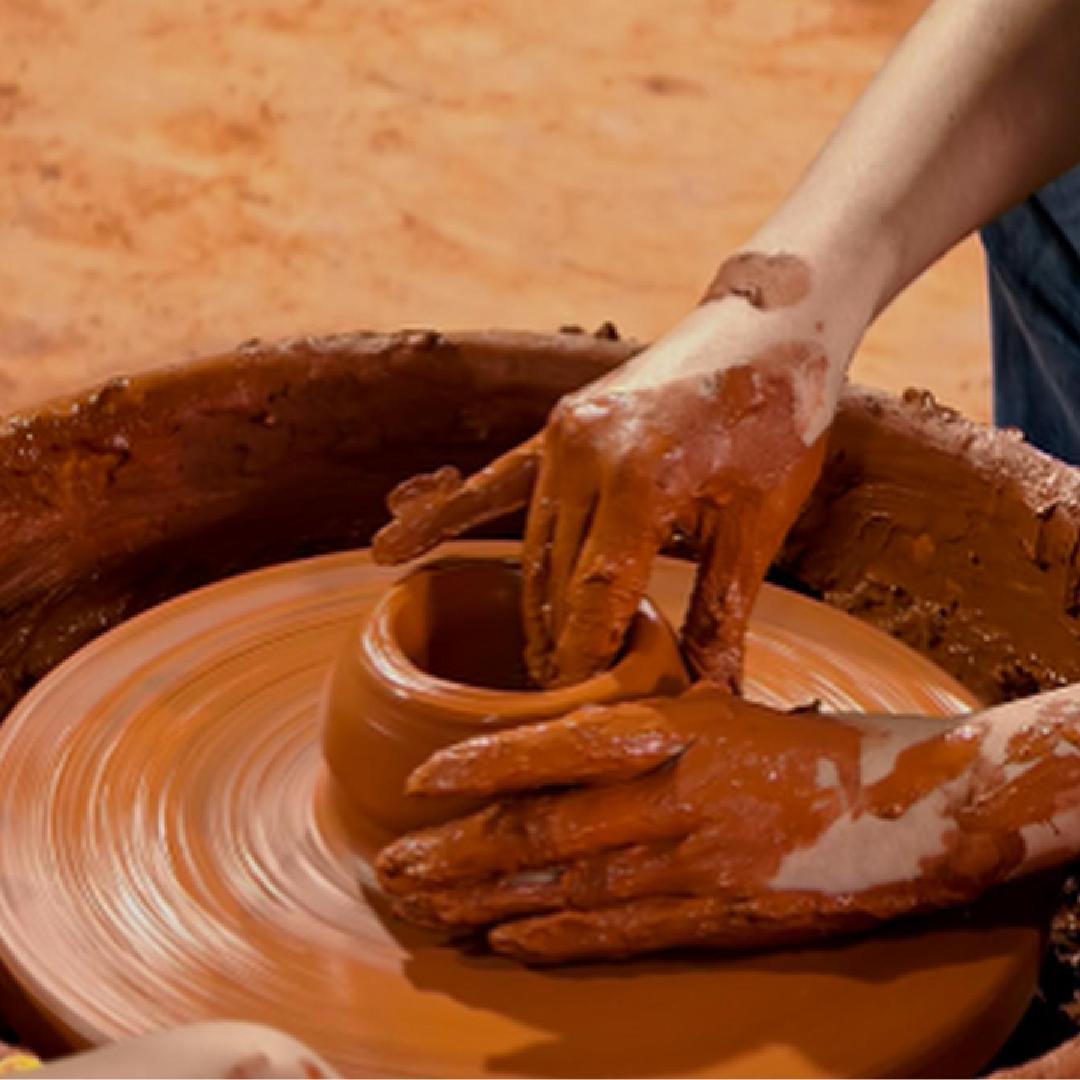 Hands shaping a ceramic vessel on a pottery wheel